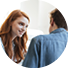 A woman with red hair and a blue shirt is smiling at a man.

Description generated by AI